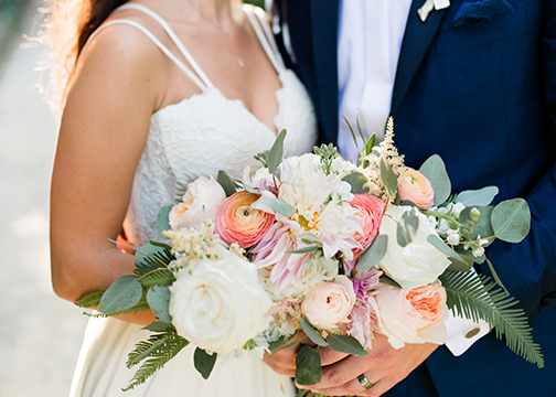 bride and groom holding bouquet tropical light pink bouquet wedding florals