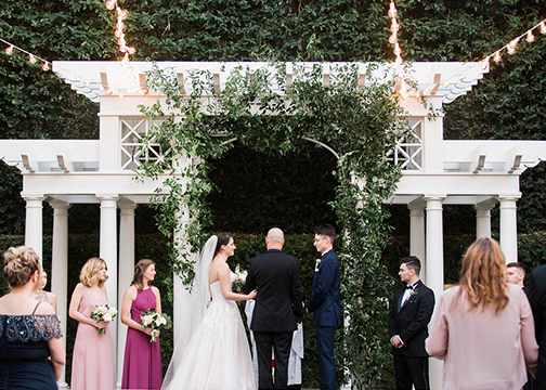 bride and groom under pergola covered in garden vines wedding flowers